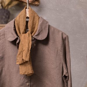 Taupe-gray linen shirt with an ochre-brown scarf, shown on a wooden hanger in a front close-up, with a rounded collar, small buttons, narrow placket, long sleeves and two scarf ends hanging at the neck.